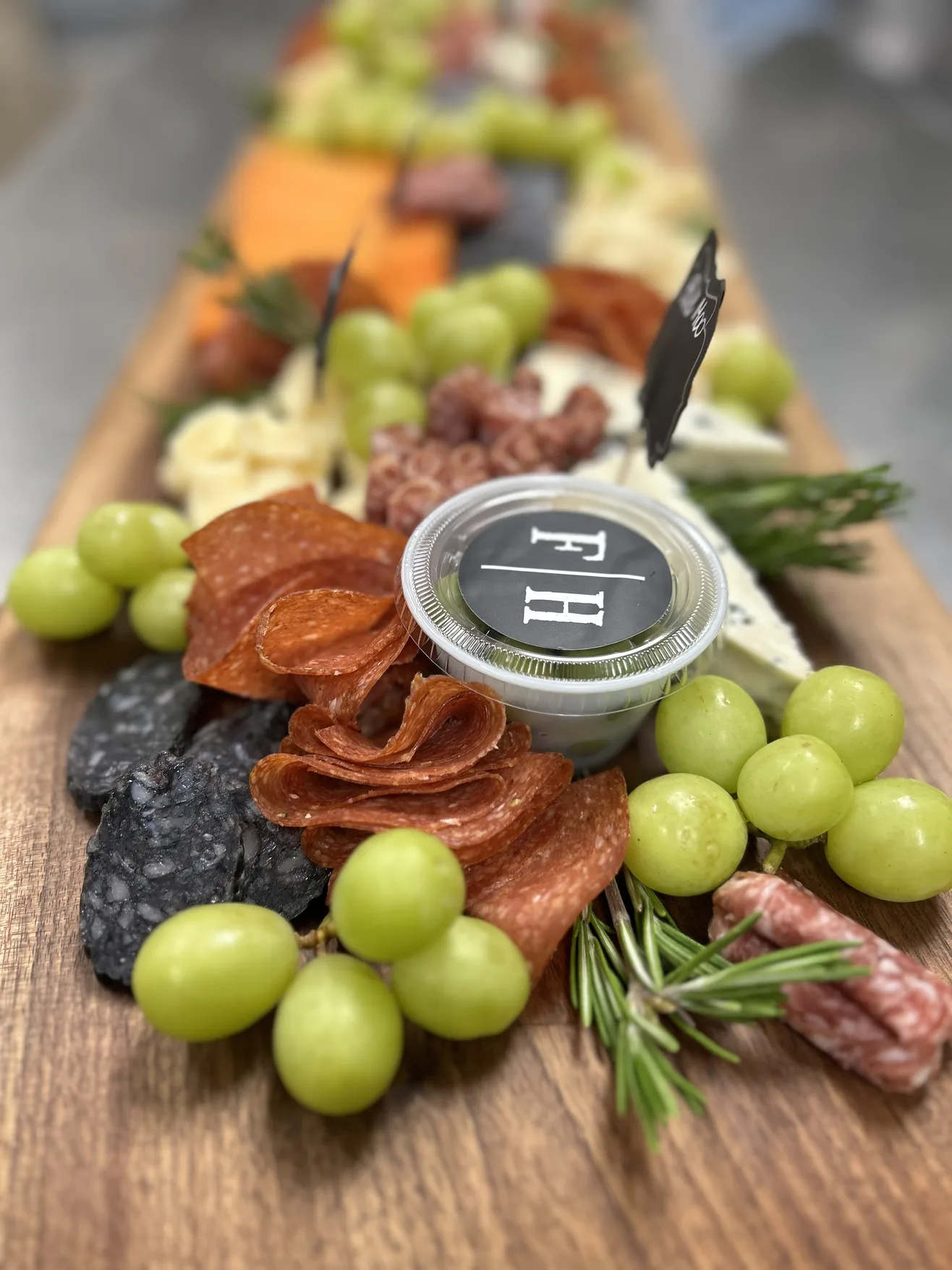 Charcuterie board with salami, cheeses, grapes and rosemary